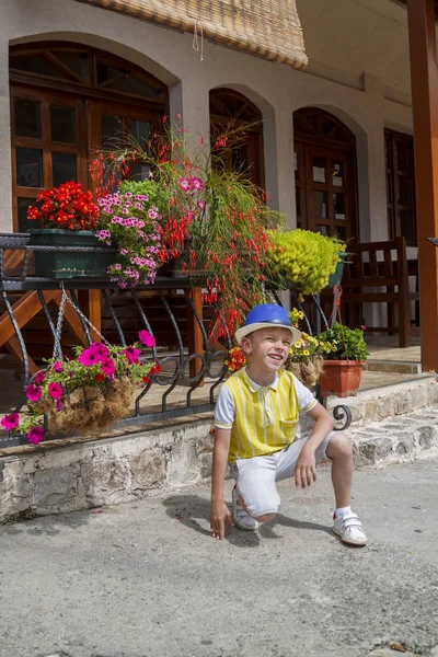 mavi şapkalı seyahat eden çocuk yakın sokakta poz oturdu 