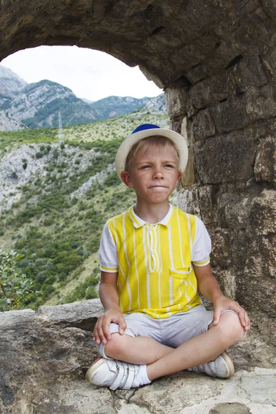 Ragazzo con un cappello blu seduto nella finestra di osservazione dell'antico — Foto Stock