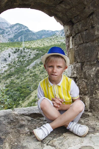 Boy in a blue hat sitting in the observation window of the ancie — Stock Photo, Image