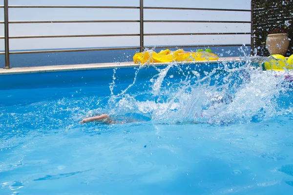 Salpicos de água após o salto do bebê na piscina — Fotografia de Stock