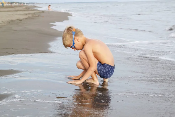 Junge mit blonden Haaren in Schwimmbrille spielt am Strand in — Stockfoto