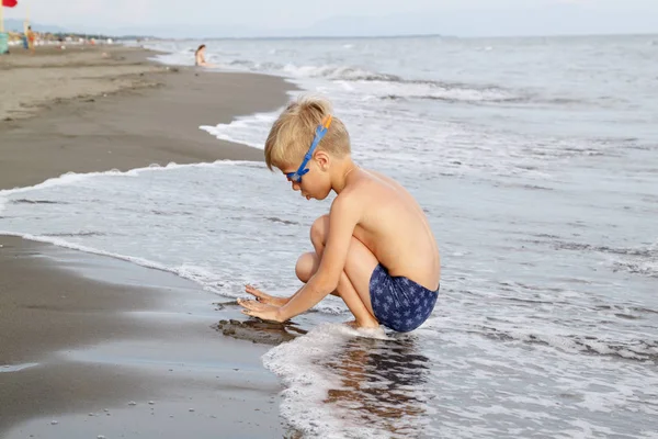 Junge mit blonden Haaren in Schwimmbrille spielt am Strand in — Stockfoto