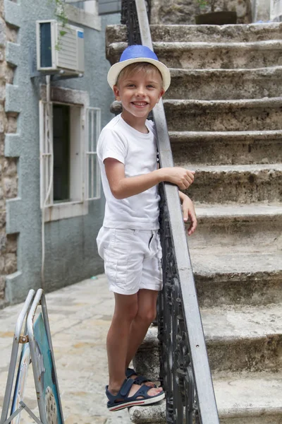 Liitle kid in a blue hat, standing on the stairs of the ancient — Stock Photo, Image