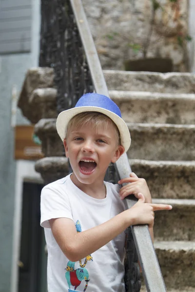 Criança liitle em um chapéu azul, de pé nas escadas do antigo — Fotografia de Stock