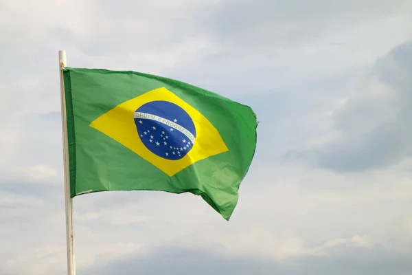 Bandeira brasileira em um céu azul com fundo de nuvens — Fotografia de Stock