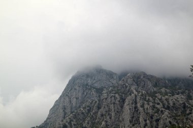 Mavi gökyüzü arka planı üzerinde beyaz bulutları olan dağlar