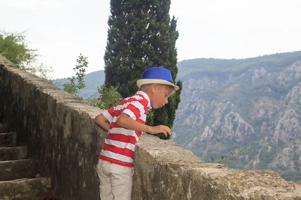 Affascinante ragazzo su per le scale in montagna, e gettando ciottoli — Foto Stock