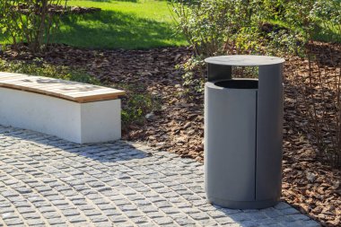 arkasında malçlı manzara ile gri minimalist çöp kutusu ve ahşap Park tezgah
