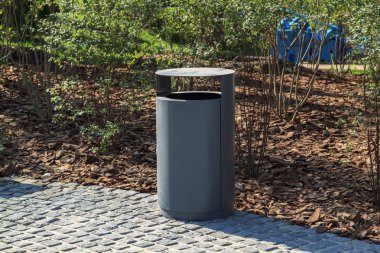 parkta malçlı manzara ile gri minimalist çöp kutusu