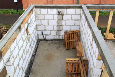 İnşaat halindeki bir kır evinin içinde. Duvarların üzerine gaz, beton bloklar ve ahşap işlemelerle inşa edildiği alan.