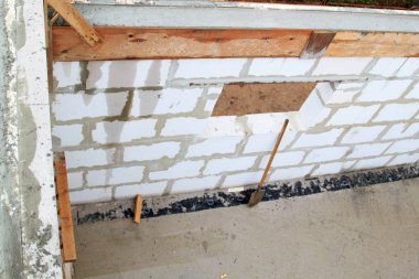 İnşaat halindeki bir kır evinin içinde. Duvarların üzerine gaz, beton bloklar ve ahşap işlemelerle inşa edildiği alan.