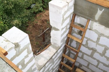 İnşaat halindeki bir kır evinin içinde. Duvarların üzerine gaz, beton bloklar ve ahşap işlemelerle inşa edildiği alan.