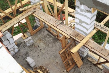 İnşaat halindeki bir kır evinin içinde. Duvarların üzerine gaz, beton bloklar ve ahşap işlemelerle inşa edildiği alan.