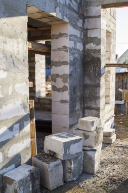 İnşaat halindeki bir kır evinin içinde. Duvarların üzerine gaz, beton bloklar ve ahşap işlemelerle inşa edildiği alan.