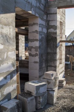 İnşaat halindeki bir kır evinin içinde. Duvarların üzerine gaz, beton bloklar ve ahşap işlemelerle inşa edildiği alan.