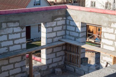 İnşaat halindeki bir kır evinin içinde. Duvarların üzerine gaz, beton bloklar ve ahşap işlemelerle inşa edildiği alan.