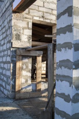 İnşaat halindeki bir kır evinin içinde. Duvarların üzerine gaz, beton bloklar ve ahşap işlemelerle inşa edildiği alan.