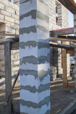 İnşaat halindeki bir kır evinin içinde. Duvarların üzerine gaz, beton bloklar ve ahşap işlemelerle inşa edildiği alan.