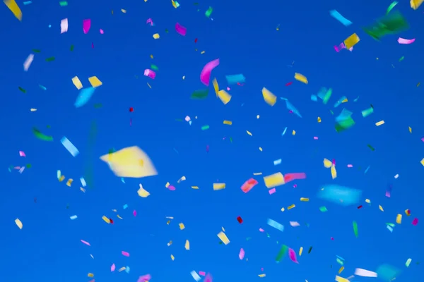 Mångfärgade konfetti på klarblå himmel bakgrund. begreppet holiday bakgrund — Stockfoto