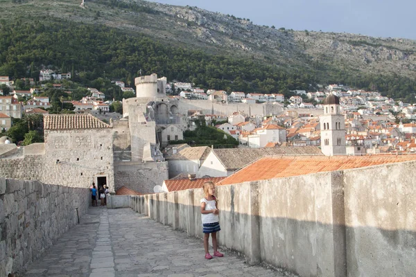 Menina nas paredes cercando a cidade velha de Dubrovnik ao pôr do sol — Fotografia de Stock