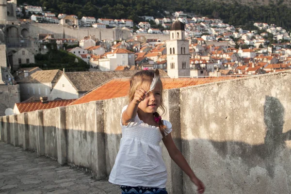 Bambina con la piuma sulle pareti che racchiude il centro storico di Dubrovnik al tramonto — Foto Stock
