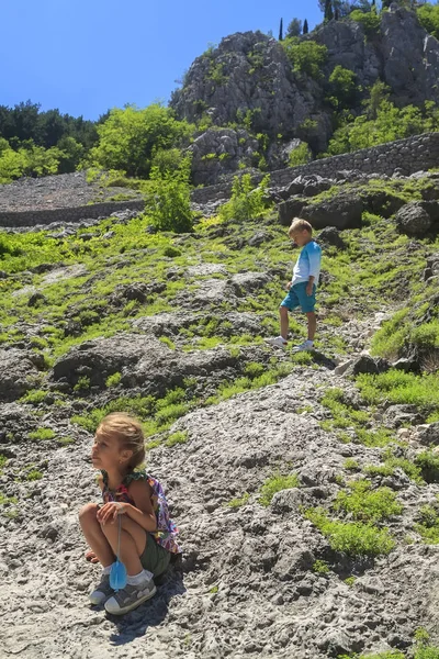Μικρό κορίτσι κάθεται σε μια βουνοπλαγιά όχι πολύ πιο ψηλά είναι γαλήνια — Φωτογραφία Αρχείου