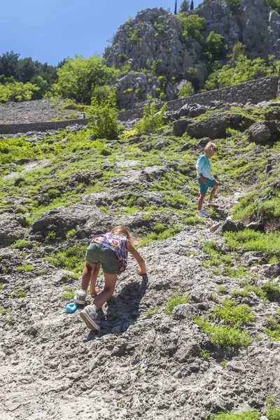 Μικρό κορίτσι αναρρίχηση σε μια βουνοπλαγιά όχι πολύ πιο πάνω είναι γαλήνια ο αδελφός της — Φωτογραφία Αρχείου