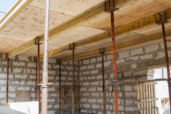 Blick auf die Holzschalung mit Metallhalterungen, die vom Schaumstoffblock aus mit der Überlappung zwischen den Fußböden des im Bau befindlichen Landhauses gefüllt wird — Stockfoto