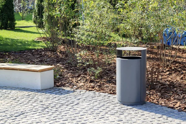 Grey minimalist dustbin and wooden Park bench with mulched lands — Stock Photo, Image