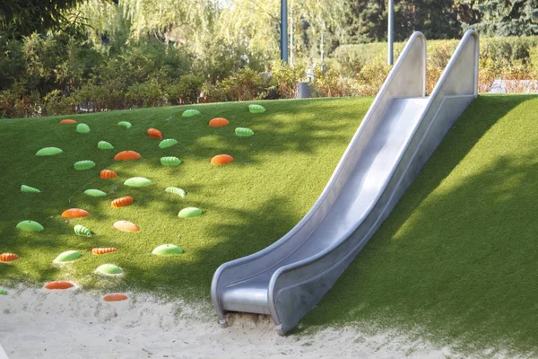 Moderner Spielplatz mit einer Metallrutsche im Landschaftsbild mit einer Leiter aus Kunststoffschalen am Hang — Stockfoto