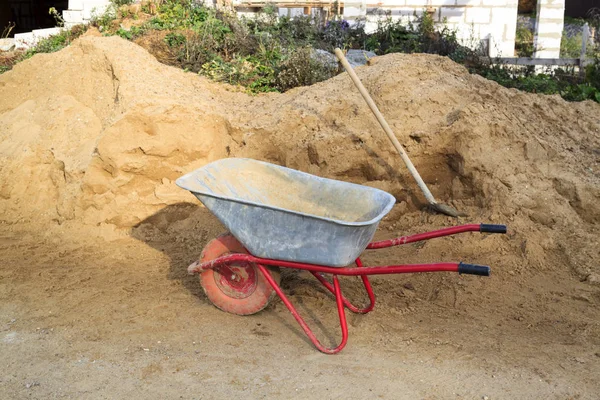 Muita areia e um carrinho de mão no canteiro de obras — Fotografia de Stock