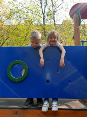 Baharda çocuk parkında duran mutlu kız ve erkek. 