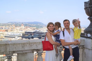 Çocuklarla keyifli bir yolculuk konsepti. Mutlu ebeveynler ve çocukları gülümseyerek kameraya bakmak ve Budapeşte, Macaristan'da St Stephen Bazilikası gözlem güvertesinde ayakta.