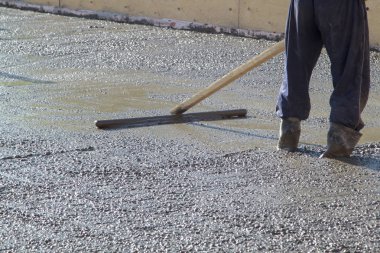 kauçuk çizmeler işçi derli toplu çimento duruyor ve özel bir ahşap çalışma aracı ile taban plakası (taze beton levha) yüzeyi tesviye