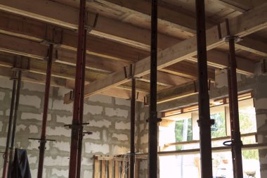 Metalik tutucularla ahşap biçimlendirme manzarası, köpük bloktan inşaat halindeki kır evindeki katlar arasında çakışacak.