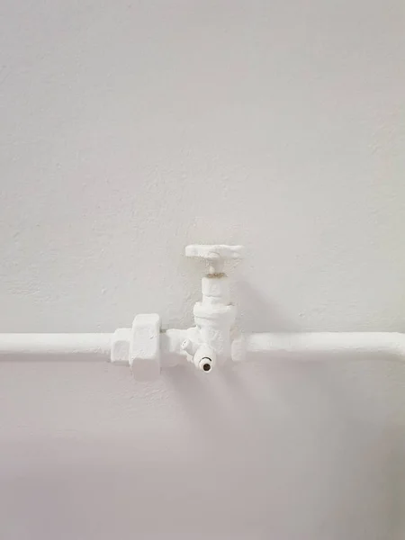 Кран с белой водой на металлической трубе на белом фоне лепнины — стоковое фото