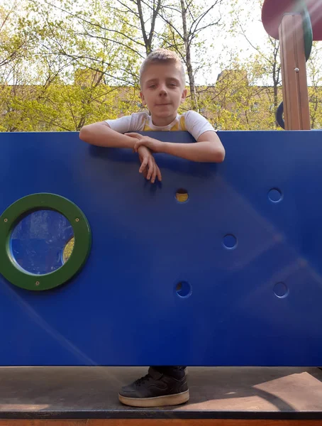 Happy boy stands on the Playground in the spring and looks at th — Stock Photo, Image