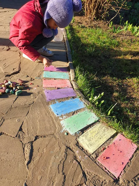 A menina desenha lápis de cor brilhante em um caminho de pedra no cou — Fotografia de Stock
