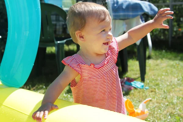 Menina adorável na camisa listrada fica no jardim — Fotografia de Stock