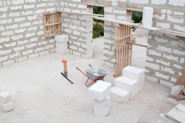 Baustelle, auf der die Wände aus Gasbetonsteinen und Schubkarren gebaut werden — Stockfoto