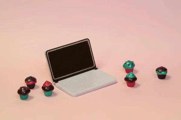 Babeczki z laptopem na różowym pastelowym tle — Zdjęcie stockowe