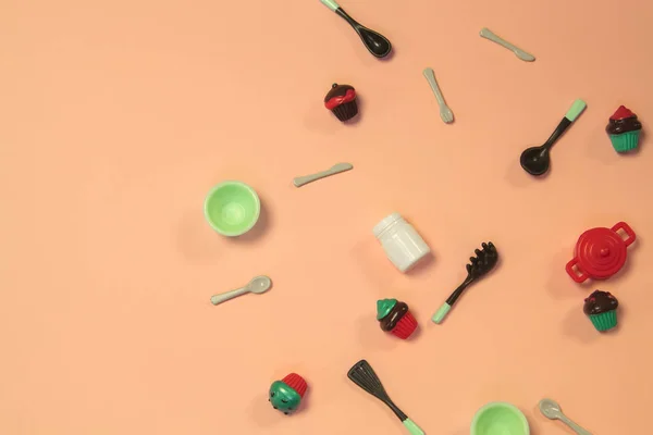 Plat lay afbeelding van plastic speelgoed servies met gebak op pastel roze achtergrond — Stockfoto