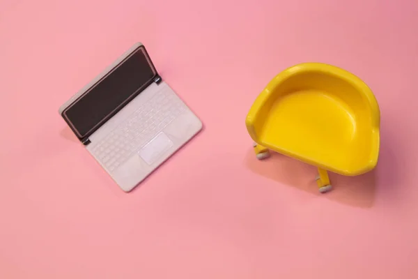 Concept van lege stoel. Gele kruk met laptop op roze pastel schone achtergrond. Foto in platte lay minimale stijl. — Stockfoto