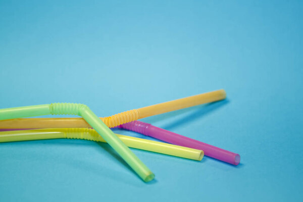 Multicolored cocktail tubes on a blue pastel background. Colorful straws flat lay image