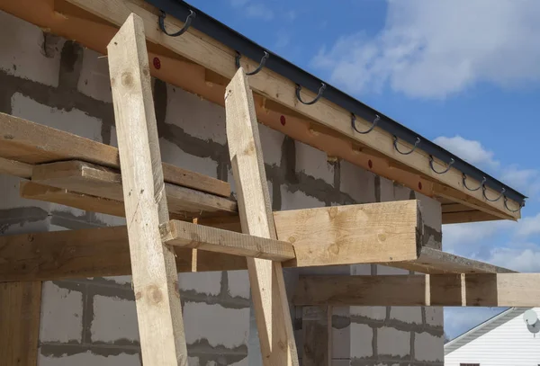 Primer plano vista de andamios y casa en construcción con soportes para canaletas sistema de drenaje de agua de techo — Foto de Stock