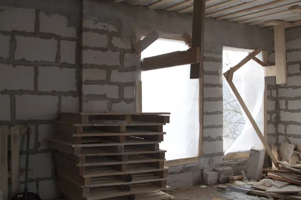 Interior de una casa de campo en construcción con madera contrachapada. Sitio en el que se construyen las paredes de bloques de hormigón a gas con andamios de madera — Foto de Stock