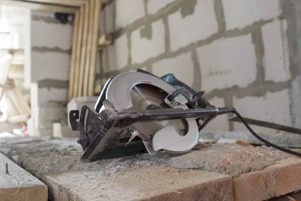 Manual circular saw is on a wooden board in house under construc — Stock Photo, Image