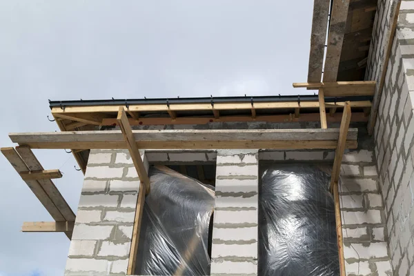 Primer plano vista de andamios y casa en construcción con soportes para canaletas sistema de drenaje de agua de techo —  Fotos de Stock