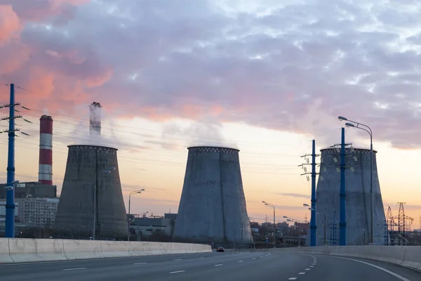 Road with cars passing in succession with heat power plant at su — ストック写真