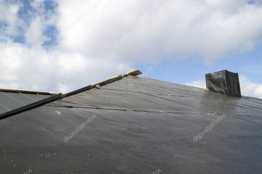 close up view of folded roof with chimney under construction on black waterproofing layer